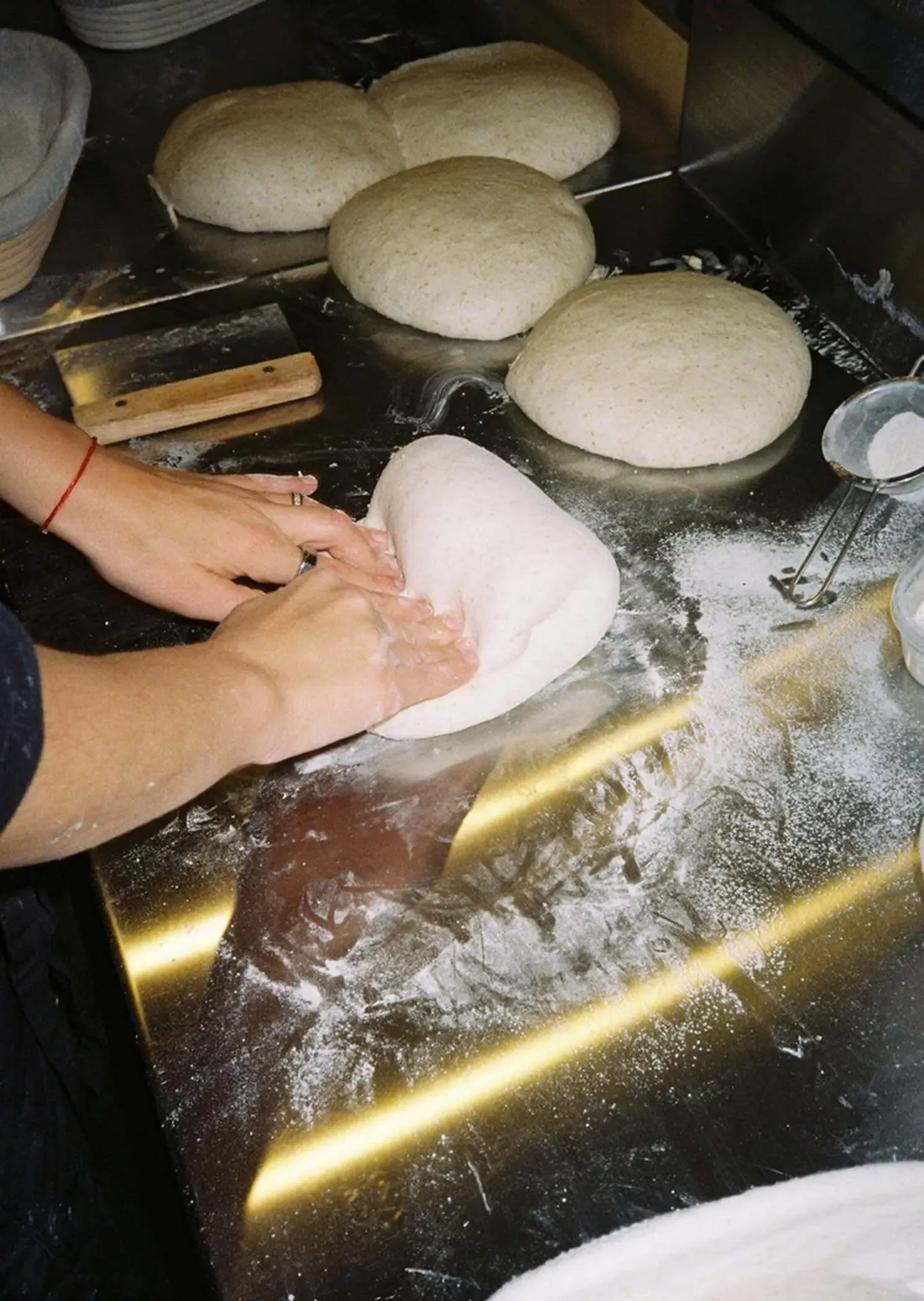 Hands shaping a loaf on the flour-covered bakery counter
