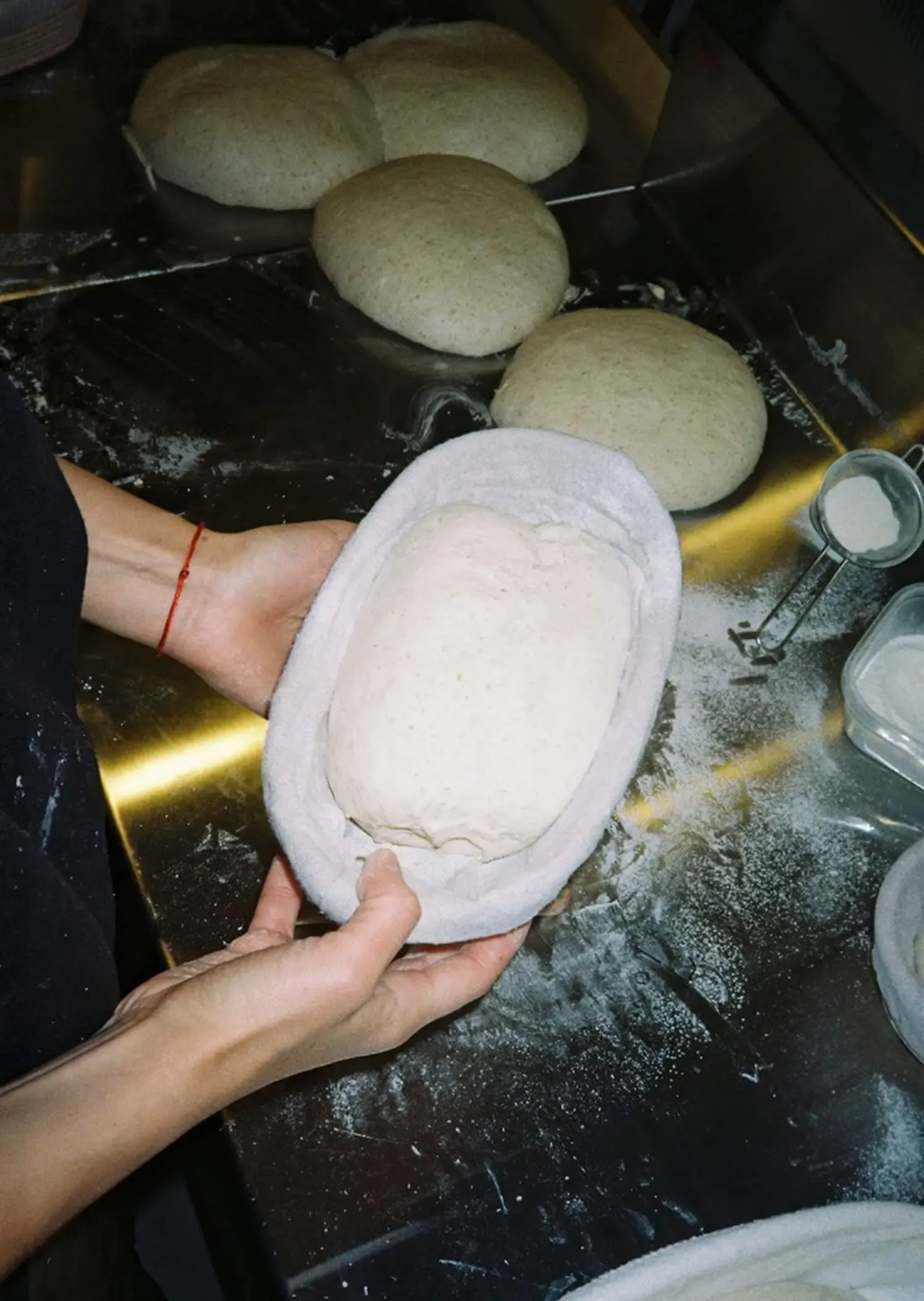 Hands holding a freshly shaped sourdough loaf