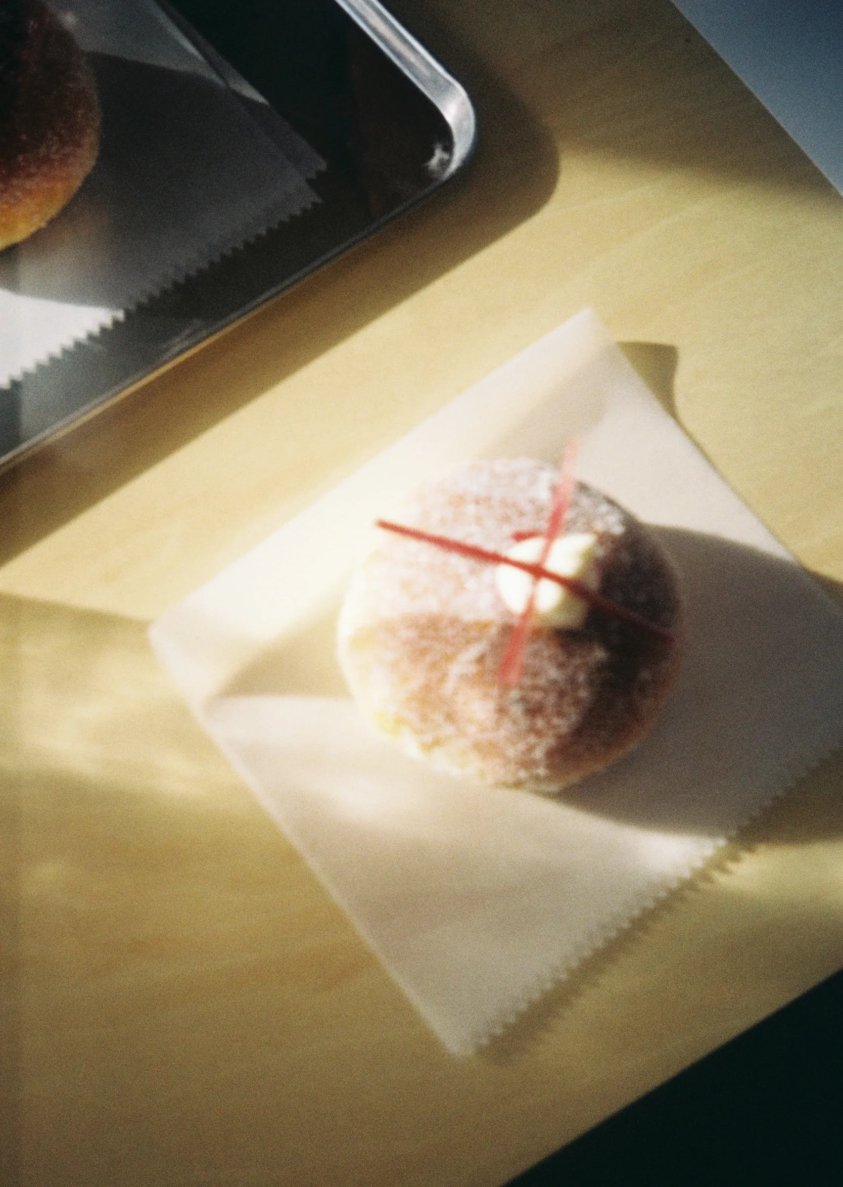 A sugar-dusted pastry wrapped with red string in morning light